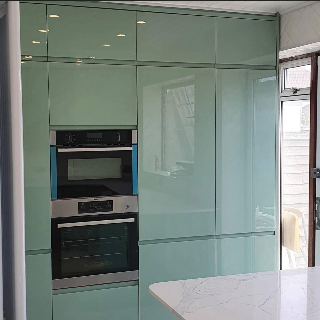 High-gloss sage green kitchen cabinets with built-in appliances