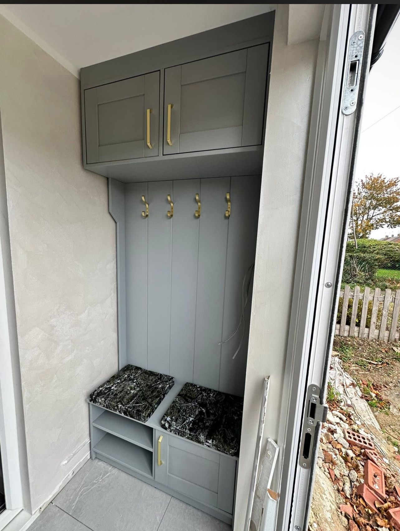 Bespoke mudroom storage unit with brass hardware and integrated bench seating